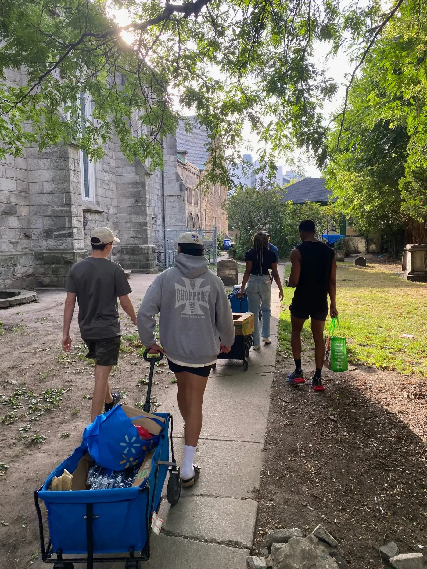 Volunteers pulling wagons of supplies through a churchyard